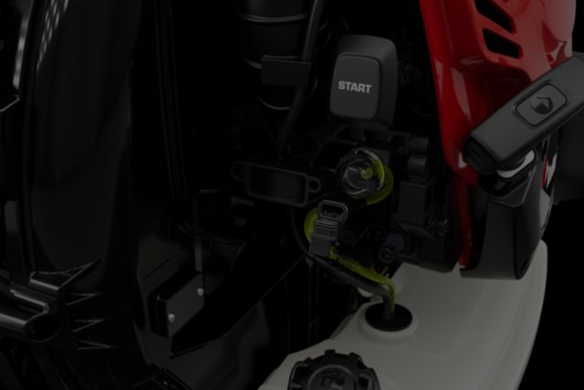Close-up view of a machine's engine compartment with a visible start button and fuel cap.