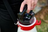 A person inserting a battery into a portable garden sprayer.