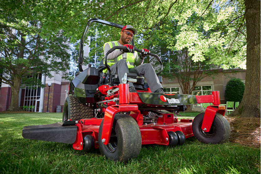 A person operating a ride-on lawn mower in a garden setting.